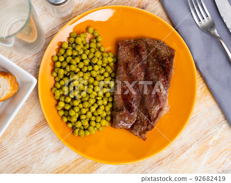 Beef steak with green peas served on plate 92682419