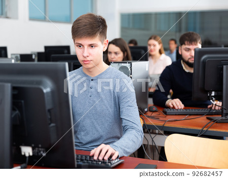 Group of people of different ages learning to use computers in classroom 92682457