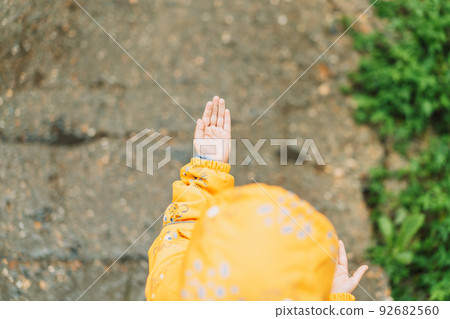 Raindrops fall on the palm of little girl in yellow suit 92682560