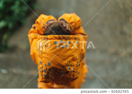 Girl in yellow rain suit standing in the rain Girl in yellow rain suit standing in the rain 92682565
