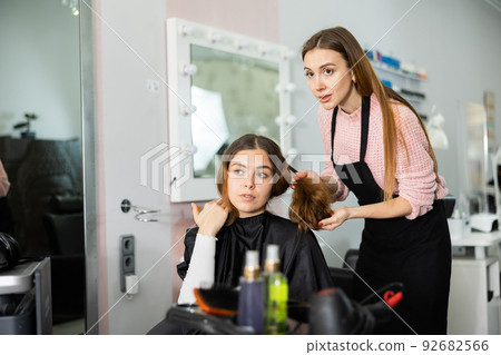 Young woman explains to the hairdresser how she wants to get a haircut Young woman explains to the hairdresser how she wants to get a haircut 92682566
