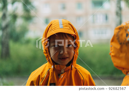 Boy in yellow rain suit standing in the rain 92682567