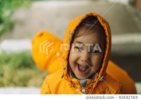 Children in yellow rain suits standing in the rain Children in yellow rain suits standing in the rain 92682569