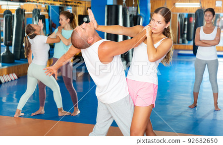 Young woman practicing palm strike with man in self defense training 92682650