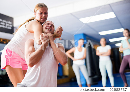 Girl practicing guillotine choke on opponent in sparring with man 92682787