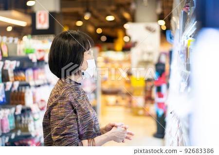 Beautiful Asian senior adult looking for cosmetic products at convenience mall during the Coronavirus, COVID19 outbreak. Social distancing and using protective face mask during the COVID-19 outbreak. Beautiful Asian senior adult looking for cosmetic products at convenience mall during the Coronavirus, COVID19 outbreak. Social distancing and using protective face mask during the COVID-19 outbreak. 92683386