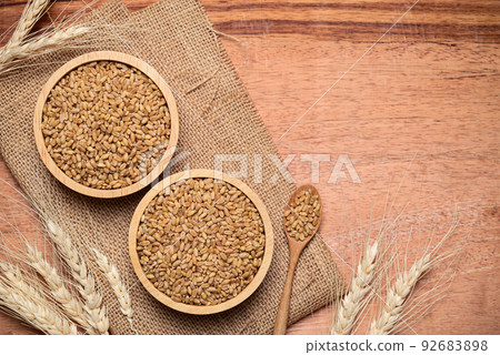 Whole wheat grain in bowl on wooden background, food ingredients, Table top view Whole wheat grain in bowl on wooden background, food ingredients, Table top view 92683898