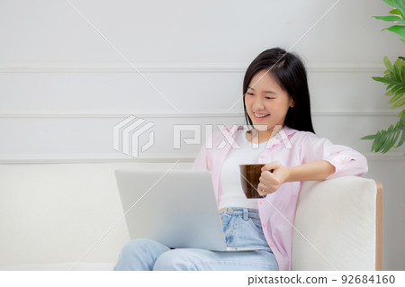 Young asian business woman work from home with laptop computer and drinking coffee on sofa. Young asian business woman work from home with laptop computer and drinking coffee on sofa. 92684160