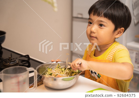 一個 4 歲的男孩在媽媽的幫助下將食材混合在一個碗裡 一個 4 歲的男孩在媽媽的幫助下將食材混合在一個碗裡 92684375
