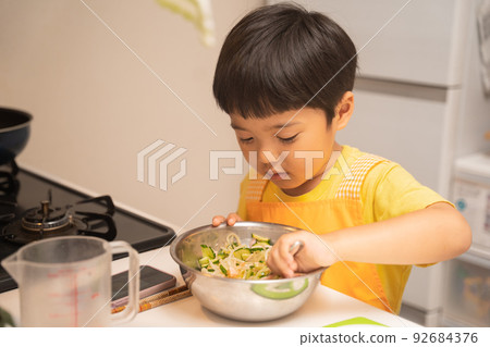 A 4-year-old boy mixes the ingredients in a bowl while looking at the recipe with the help of his mother. A 4-year-old boy mixes the ingredients in a bowl while looking at the recipe with the help of his mother. 92684376