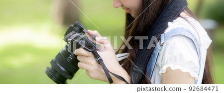 Beautiful happiness young asian woman using camera take a photo for relax in the park. 92684471