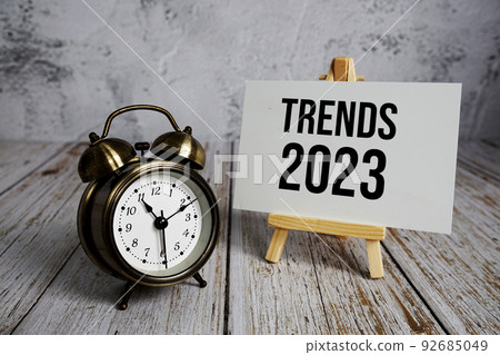 Trends 2023 text message and alarm clock on wooden background Trends 2023 text message and alarm clock on wooden background 92685049