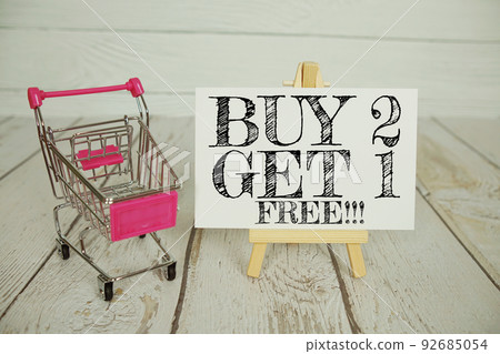 Buy 2 Get 1 Free text message and shopping trolley cart on wooden background 92685054