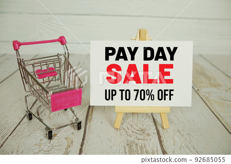Pay Day Sale text message and shopping trolley cart on wooden background 92685055