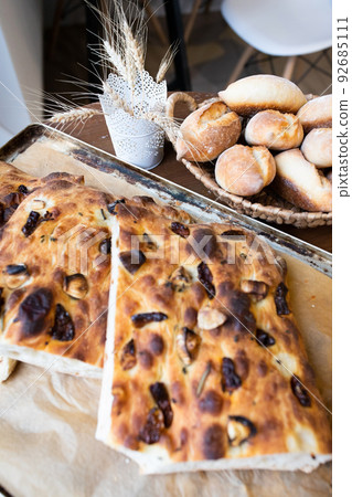 Traditional Italian focaccia bread on a tray surrounded by other bread. Photo from a small artisan bakery. Vertical photo. 92685111
