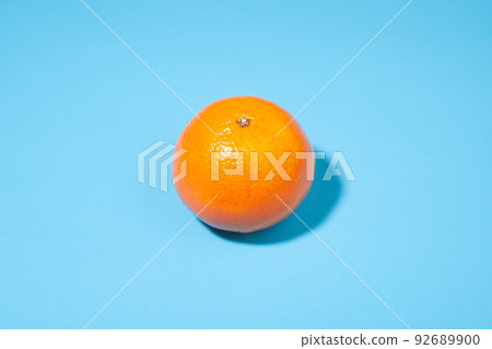 Bright orange tangerine close-up on a blue background Bright orange tangerine close-up on a blue background 92689900