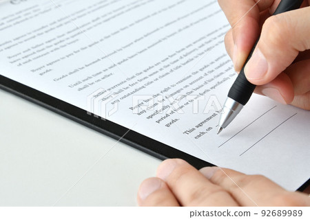 Person's hand signing a contract in English 92689989