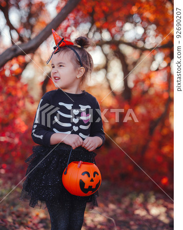 Young girl in black costume goes trick or treating 92690207