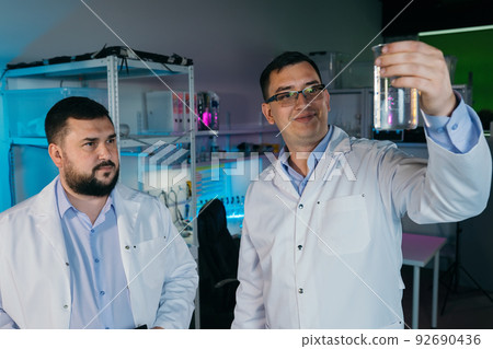 Two male laboratory assistants are doing research on chemicals Two male laboratory assistants are doing research on chemicals 92690436