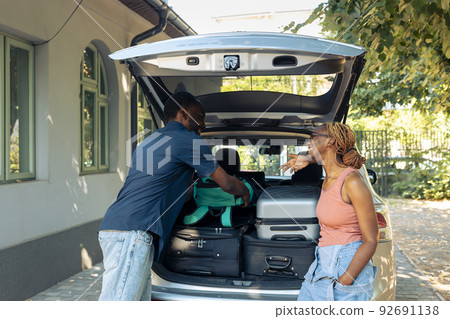 People in relationship loading suitcase in trunk to leave on summer holiday trip, preparing baggage and trolley in vehicle. Couple in love travelling together on vacation, packing bags in car. People in relationship loading suitcase in trunk to leave on summer holiday trip, preparing baggage and trolley in vehicle. Couple in love travelling together on vacation, packing bags in car. 92691138
