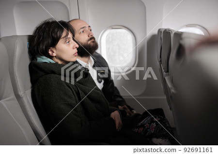 Caucasian travellers having conversation on commercial flight, travelling by plane to go on holiday journey destination. Couple flying abroad with airplane transport to arrive on vacation. Caucasian travellers having conversation on commercial flight, travelling by plane to go on holiday journey destination. Couple flying abroad with airplane transport to arrive on vacation. 92691161