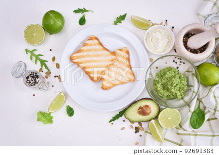 Toasts preparation - grilled toast bread and mashed avocado Toasts preparation - grilled toast bread and mashed avocado 92691383
