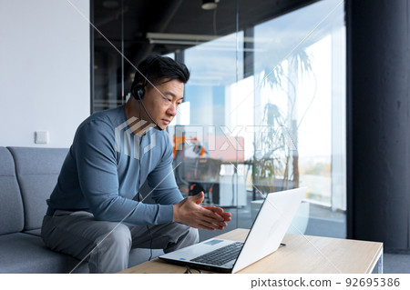 portrait of an Asian call center employee, man working with headset and computer, remote work, video call, online help portrait of an Asian call center employee, man working with headset and computer, remote work, video call, online help 92695386