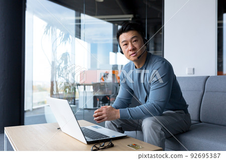 portrait of an Asian call center employee, man working with headset and computer, remote work, video call, online help portrait of an Asian call center employee, man working with headset and computer, remote work, video call, online help 92695387