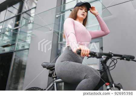 Serious athletic woman on a bicycle straightens a cap Serious athletic woman on a bicycle straightens a cap 92695398