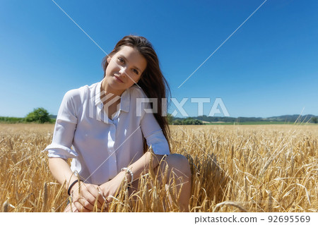 Young brunette is posing in a wheat field Young brunette is posing in a wheat field 92695569