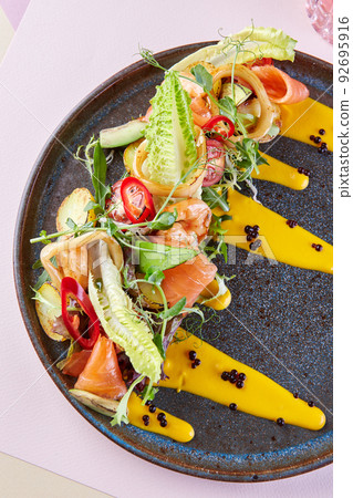 Beautiful restaurant serving dishes of red fish and vegetables and sauce Beautiful restaurant serving dishes of red fish and vegetables and sauce 92695916