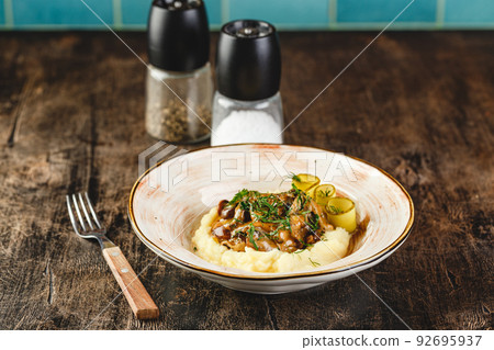 Beef Stroganoff with mashed potatoes and pickled cucumber slices in plate on wooden table in cafe. Russian style 92695937