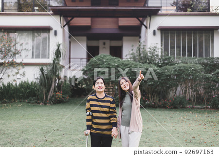 Caregiver take care to senior woman hand holding crutch try to walking at outdoor,Physical therapy concept Caregiver take care to senior woman hand holding crutch try to walking at outdoor,Physical therapy concept 92697163