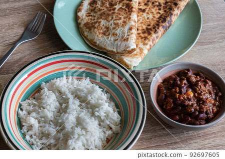 Chili con carne in a bowl accompanied by white rice and quesadillas Chili con carne in a bowl accompanied by white rice and quesadillas 92697605