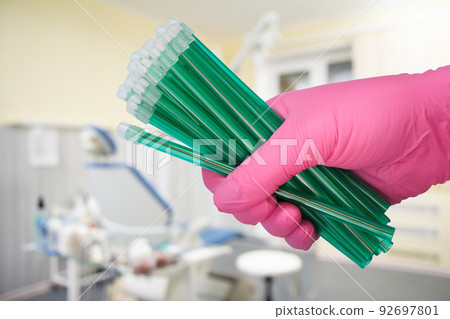 Dentist's hand in glove with saliva ejectors. Dentist's hand in glove with saliva ejectors. 92697801