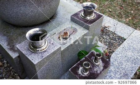 Water bowl and flower stand in front of the stone monument 92697866