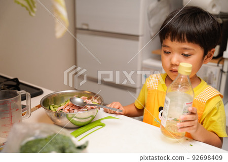 A 4-year-old boy who is trying to add seasonings to his aemono with his mother's help, but is a little unsure if it is really good A 4-year-old boy who is trying to add seasonings to his aemono with his mother's help, but is a little unsure if it is really good 92698409
