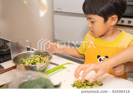 4歲男孩把黃瓜放在碗裡幫媽媽做飯 92698418