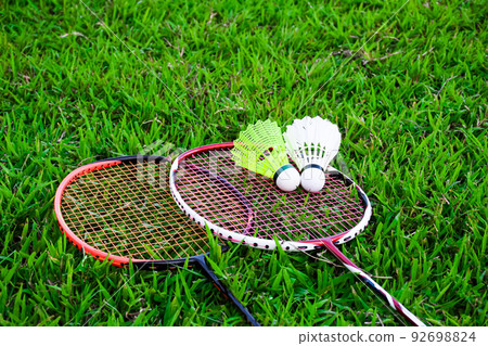 Shuttlecocks and badminton rackets on the green field 92698824