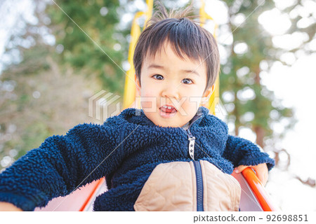 一個孩子高興地從滑梯上滑下來 92698851