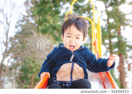 一個孩子高興地滑下滑梯 92698853