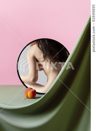 Cropped female body, back on mirror reflection with peach. Body art, aesthetics. 92699895