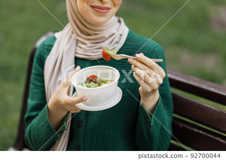 Muslim woman holding a vegetable salad in a plastic bowl in. 92700044
