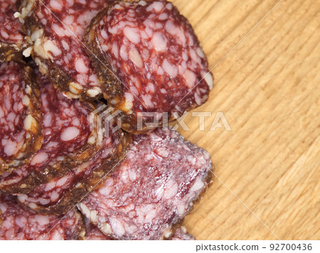 Pieces of delicious smoked sausage on a wooden cutting board, a close-up shot, a place for text. Pieces of delicious smoked sausage on a wooden cutting board, a close-up shot, a place for text. 92700436
