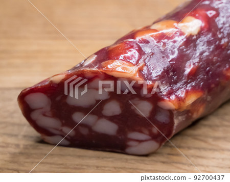 Smoked sausage on a wooden cutting board, food close-up shot. Sausage with a lot of fat. Delicacy dried sausage for food illustration. Tasty sausage on chopping board, macro Smoked sausage on a wooden cutting board, food close-up shot. Sausage with a lot of fat. Delicacy dried sausage for food illustration. Tasty sausage on chopping board, macro 92700437