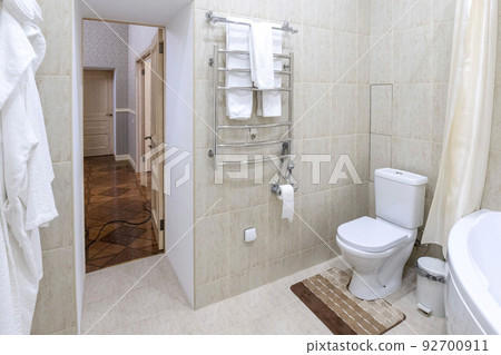 Bathroom with white sink and toilet. White bathrobes for guests hang on the wall 92700911