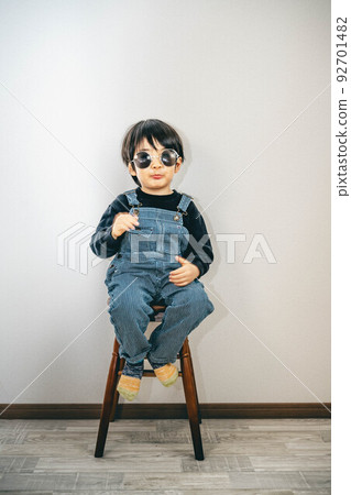 Child wearing sunglasses sitting on a chair 92701482