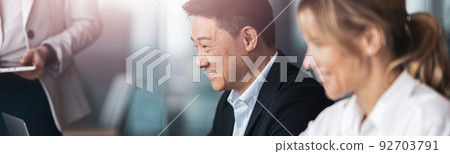 Smiling Business people in meeting room discuss project using laptop 92703791