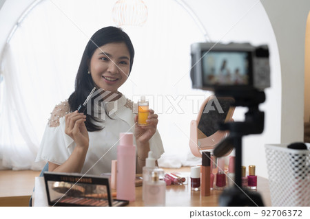 Trendy millenial beauty woman blogger stylist hold in hand cosmetic equipment. Online web broadcast internet on home background concept 92706372