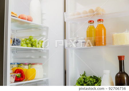 Front View of open two door fridge or refrigerator door filled with fresh fruits and vegetables, full of healthy food items and ingredients inside. Electric Kitchen and Domestic Major Appliances 92706736